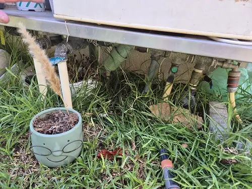 צנרת מים חיצונית סמוכה ליחידת מזגן בגינה עם גישה מוגבלת לבדיקה