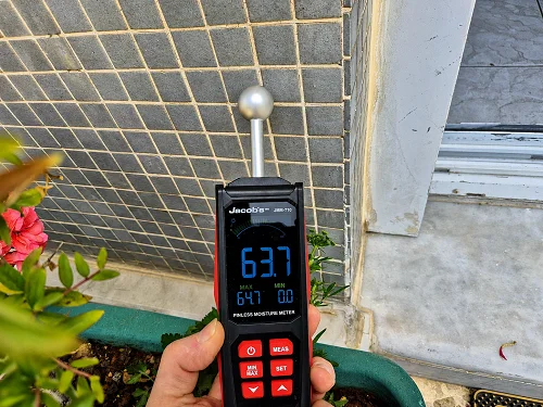 מדידת לחות בקיר חוץ סמוך לגינה כחלק מאבחון קווי מים חיצוניים